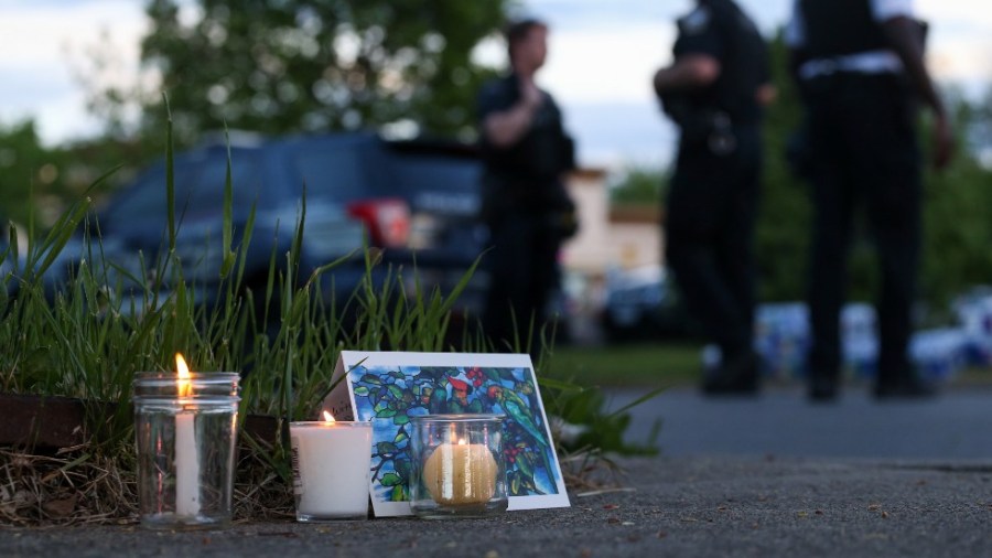 Police walk by a small memorial as they investigate after a shooting at a supermarket on Saturday, May 14, 2022, in Buffalo, N.Y.