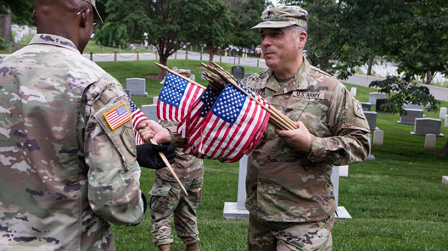 Flags are placed in front of more than 280,000 headstones of U.S. military personnel buried at Arlington National Cemetery, in preparation for Memorial Day, in Arlington, Va., on Thursday, May 26, 2022.