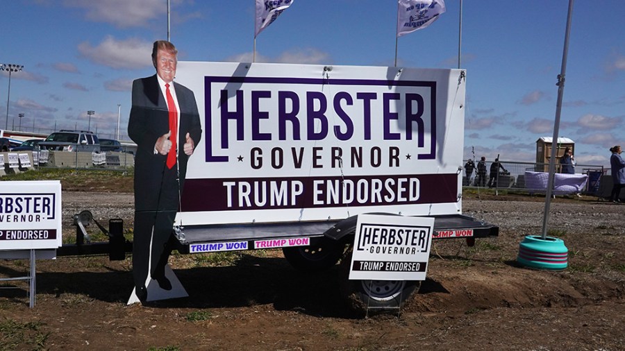 A cutout of former President Trump stands beside a sign for Charles Herbster