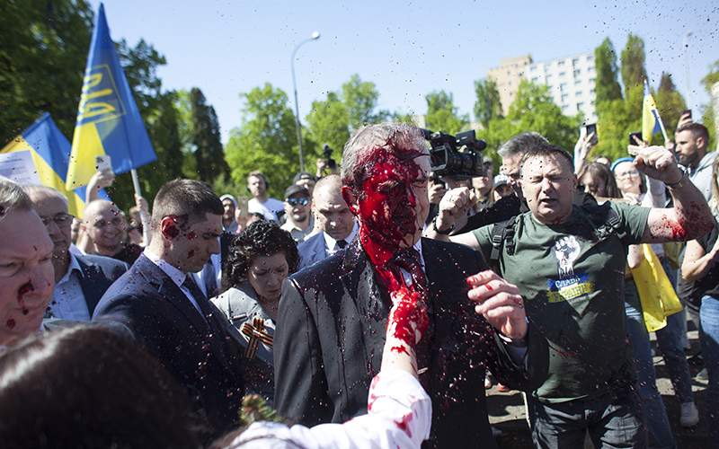 Protesters waving Ukrainian flags throw red paint on Russian Ambassador to Poland Sergey Andreev