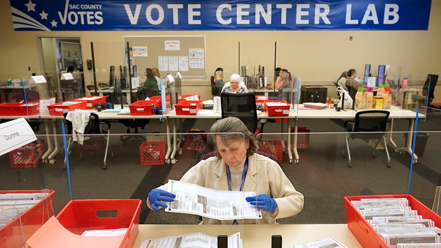 Election worker Donna Young inspects a mail-in ballot