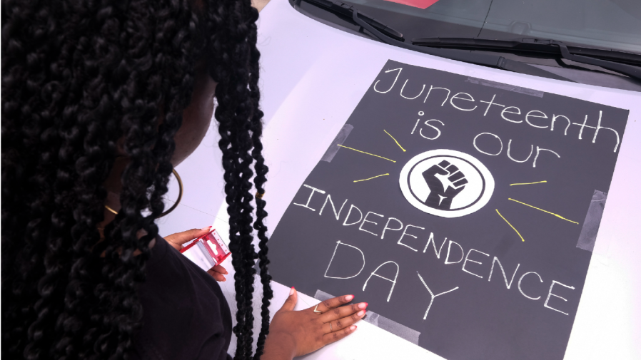 A woman decorates her car with a sign during a car parade to mark Juneteenth on Saturday, June 19, 2021, in Inglewood, Calif.