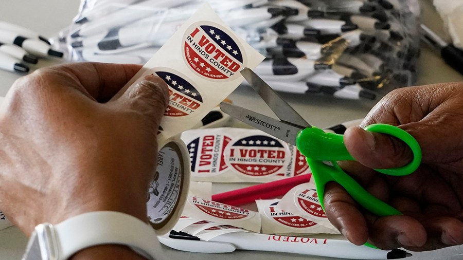 An election worker cuts "I voted" stickers from a roll