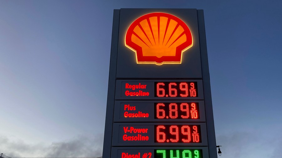 A price board is shown at a gas station