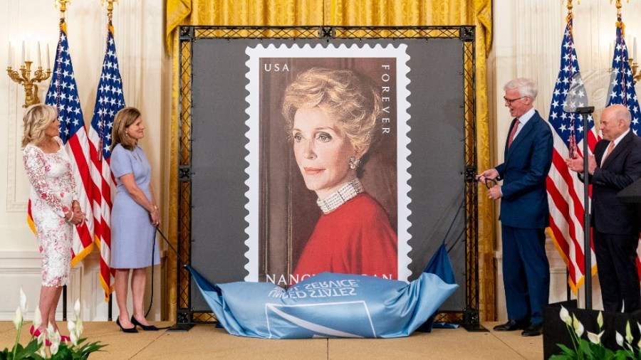 First lady Jill Biden, Postmaster General and Chief Executive Officer Louis DeJoy, Ronald Reagan Presidential Foundation and Institue Board of Trustees Chairman Fred Ryan, and Mrs. Reagan's niece Anne Peterson, unveils a new U.S. Postal Service stamp of former first lady Nancy Reagan in the East Room of the White House