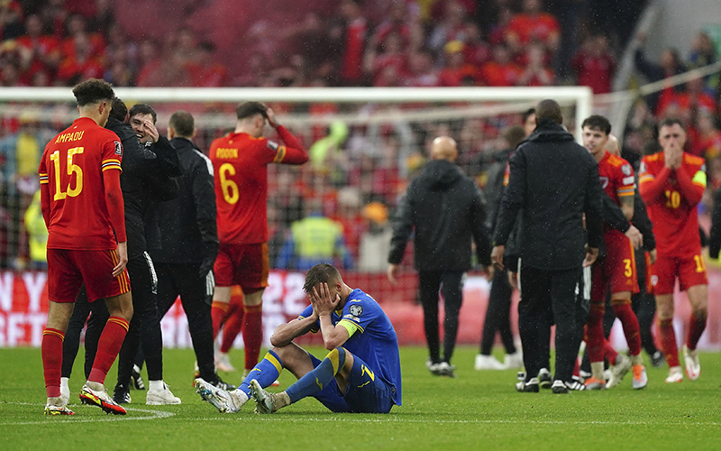 Ukraine's Andriy Yarmolenko reacts, seated on the field as Wales players walk past