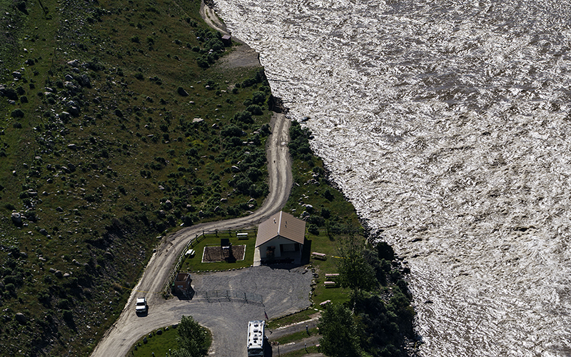 An aerial view shows a road ending where floodwaters, still raging, washed away a house