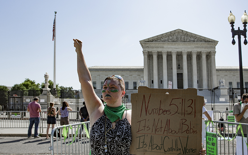 An abortion rights supporter demonstrates in front of the Supreme Court with a sign that reads, "Numbers 5:11-31 / It's Not About Babies / It's About Controlling Women"