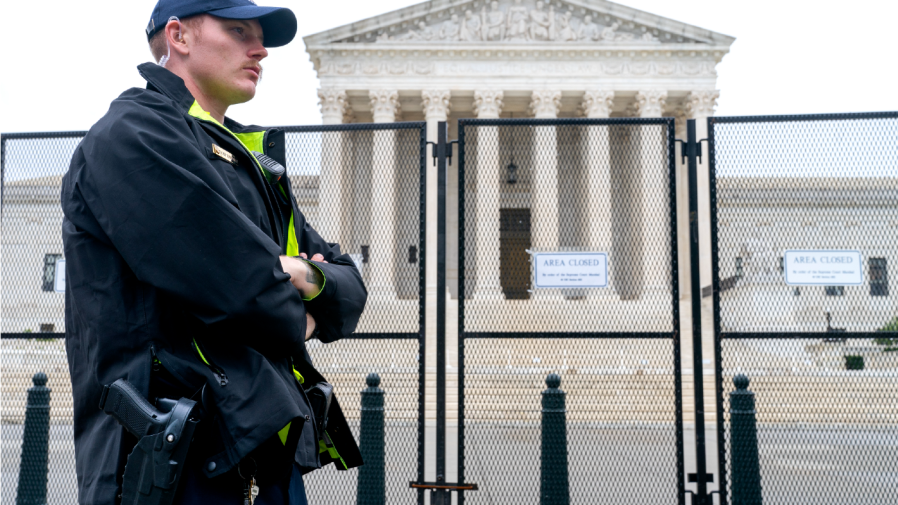 A Capitol Police Officer works by the anti-scaling fencing outside the Supreme Court, Thursday, June 23, 2022, in Washington.