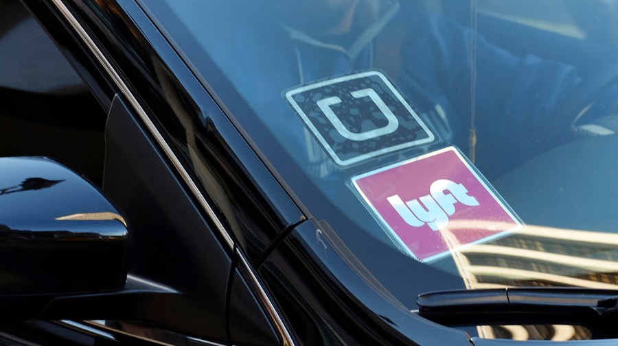 A ride share car displays Lyft and Uber stickers