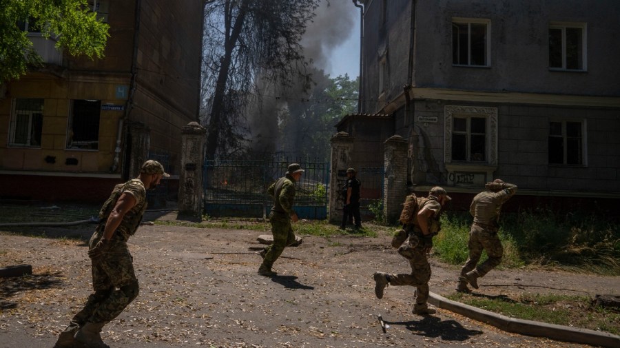 Ukrainian soldiers run after a missile strike hit a residential area, in Kramatorsk, Donetsk region, eastern Ukraine, Thursday, July 7, 2022.