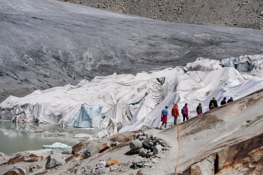 People visit the Rhone Glacier covered in blankets