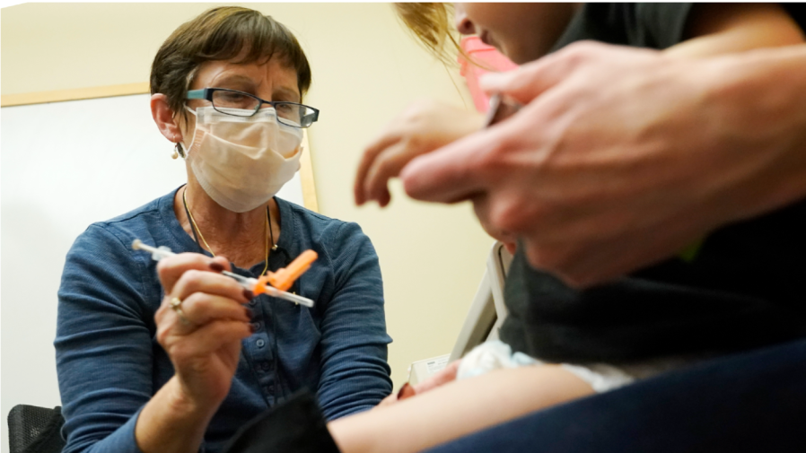 Deborah Sampson, left, a nurse at a University of Washington Medical Center clinic in Seattle, gives a Pfizer COVID-19 vaccine shot to a 20-month-old child, Tuesday, June 21, 2022, in Seattle.