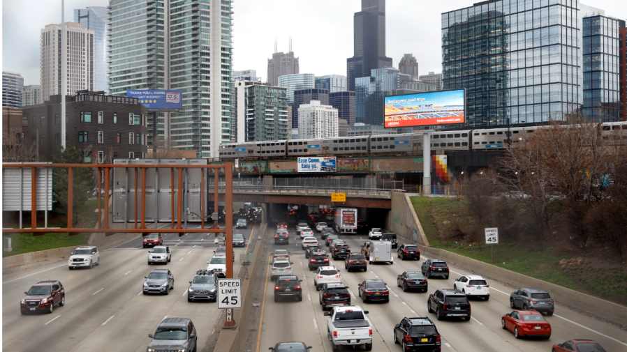 FILE - Traffic flows along Interstate 90 highway as a Metra suburban commuter train moves along an elevated track in Chicago on March 31, 2021.