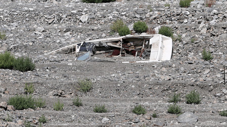 A boat rests on its side in a dried lake bed.