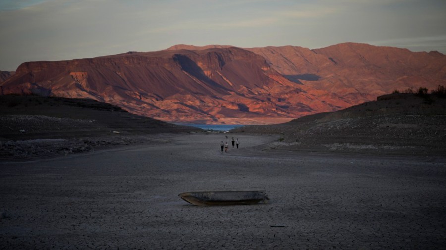 A formerly sunken boat sits on cracked earth hundreds of feet from what is now the shoreline on Lake Mead.