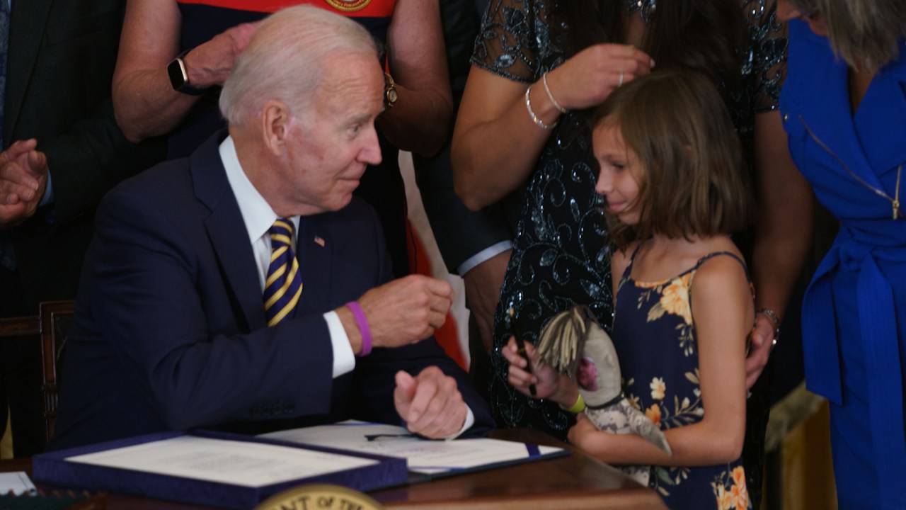 President Biden hands a pen to Brielle Robinson, daughter of the late Sgt. First Class Heath Robinson, during a ceremony to sign the Sergeant First Class Heath Robinson Honoring our Promises to Address Comprehensive Toxics Act in the East Room of the White House in Washington, D.C., on Wednesday, August 10, 2022.