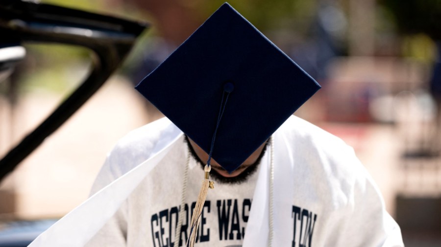 Maxxwell, a recent graduate of George Washington University, looks down while taking graduation photos in Washington, DC, on August 23, 2022.