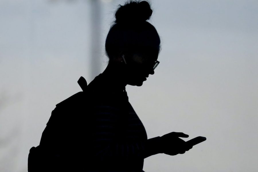 FILE - A woman checks her phone in Orem, Utah, on Nov. 14, 2019. (AP Photo/Rick Bowmer, File)