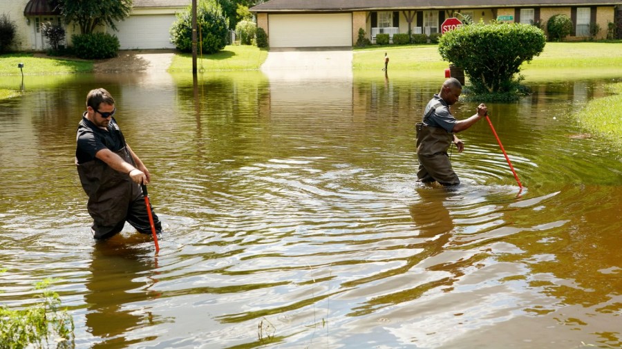 Hinds County Emergency Management Operations deputy director Tracy Funches, right, and operations coordinator Luke Chennault, wade through flood waters in northeast Jackson, Miss., Monday, Aug. 29, 2022.