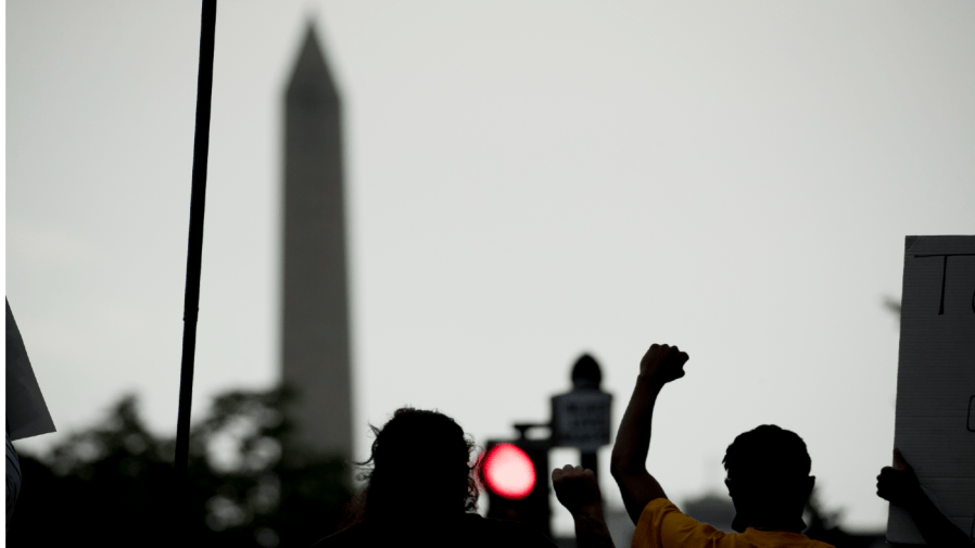 The Washington Monument is visible as people hold up fists on 16th Street Northwest renamed Black Lives Matter Plaza near the White House in Washington, Friday, June 19, 2020, on Juneteenth, the holiday celebrating the day in 1865 that enslaved black people in Galveston, Texas, learned they had been freed from bondage, more than two years after the Emancipation Proclamation.