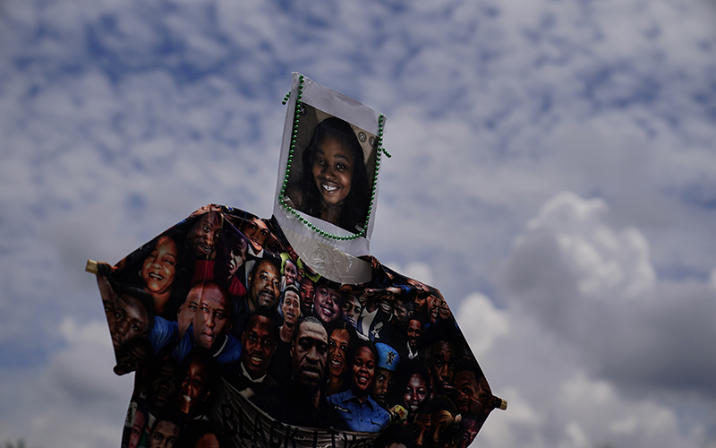 A person holds up a shirt and a piece of paper with Brianna Grier's face during a protest