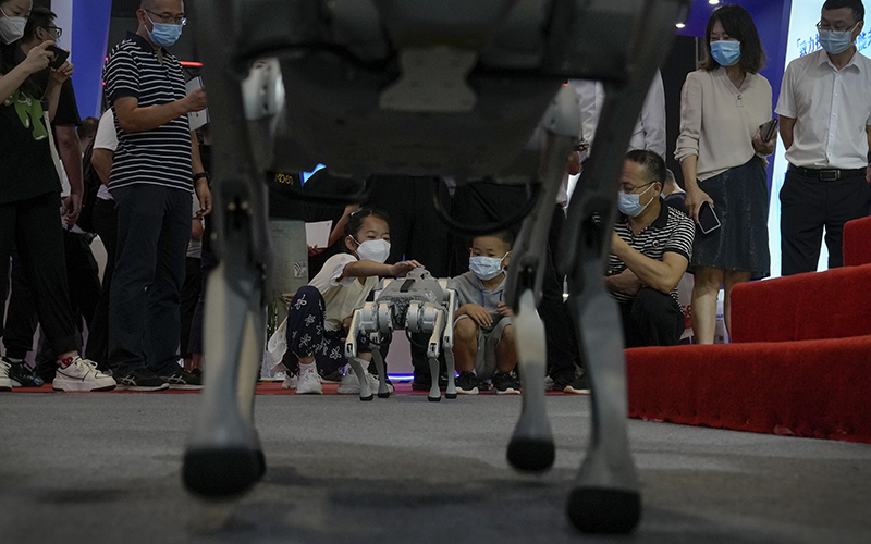 Children wearing face masks play with a robot