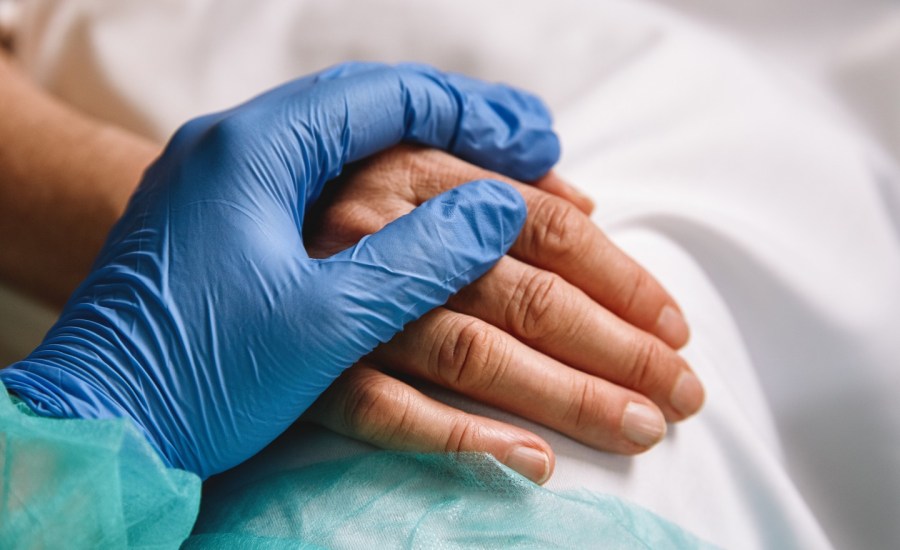 hospital patient's hand with a gloved hand resting on top