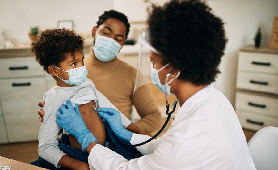 female pediatrician listening to lungs of child