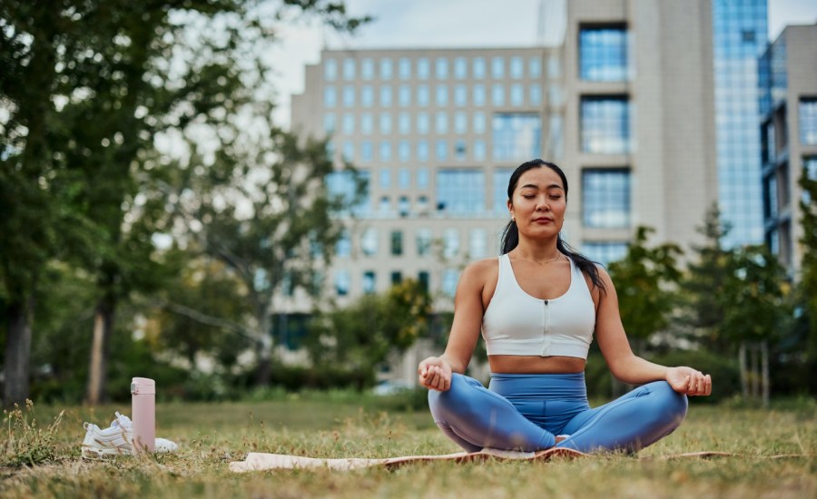 woman sitting with eyes closed on the grass in a park