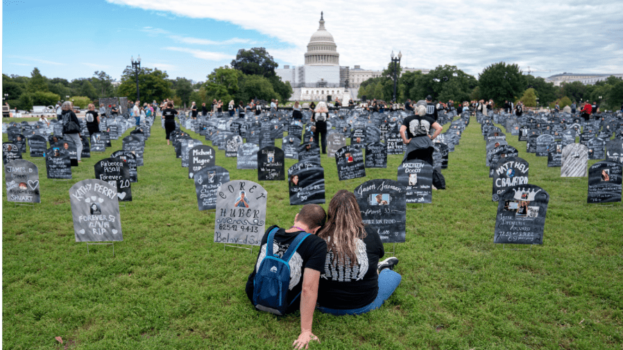 People who lost relatives to a drug overdose sit among imitation graves set up near the US Capitol in Washington, DC, on September 24, 2022.