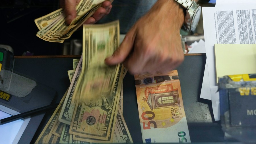 A cashier changes a 50 Euro banknote with US dollars at an exchange counter in Rome