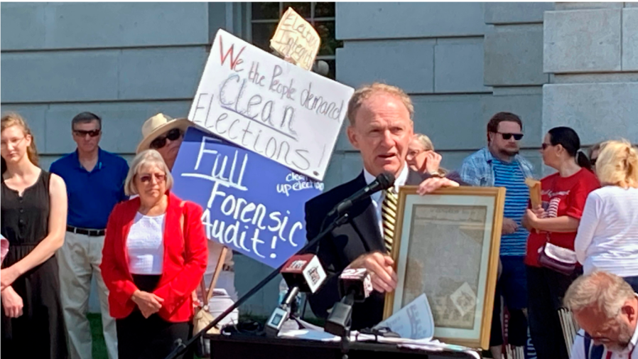 FILE- Jefferson E. Davis, spokesman for a group pushing for a broad review of the 2020 presidential election in Wisconsin, holds up a copy of the Declaration of Independence before leading a group of about 100 people into the state Capitol offices of Republican state leaders asking them to sign subpoenas for access to voting machines, ballots and other election material, on Sept. 10, 2021, in Madison, Wis.