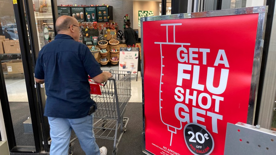 A shopper passes a sign urging people to get a flu shot