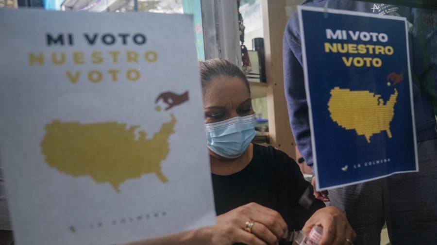 Salon owner Alejandra Moran tapes flyers to a door as part of a campaign to get voters to the polls by La Colmena, a community-based organization working with immigrant workers, in the largely Hispanic community of Port Richmond in Staten Island, N.Y., Friday, Oct. 23, 2020.