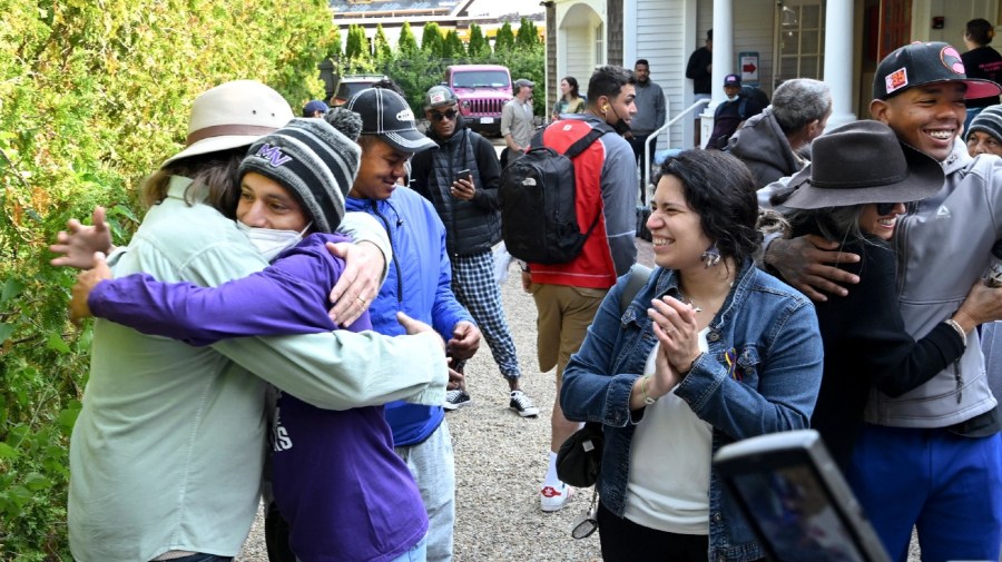 Carlos Munoz reaches out to hug Larkin Stallings of Vineyard Haven, Mass., as the immigrants prepare to leave St. Andrews in Edgartown, Mass., Friday, Sept. 16, 2022.