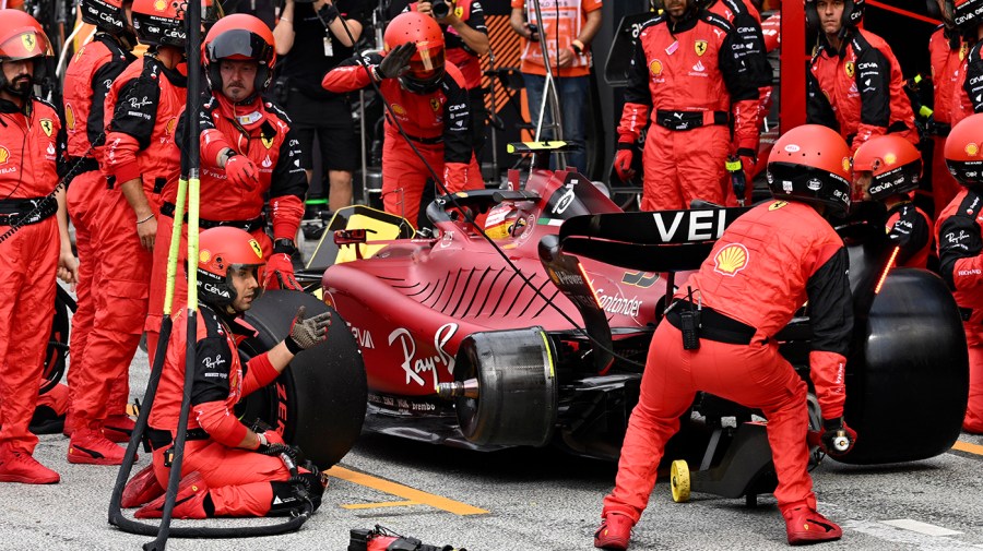 Ferrari mechanics wait for a tire to mount on the car of driver Carlos Sainz