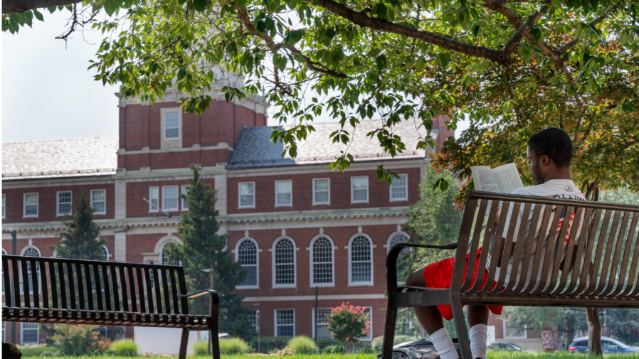 FILE - With the Founders Library in the background, a young man reads on Howard University campus July 6, 2021, in Washington.