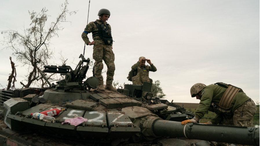 Ukrainian servicemen stand atop a destroyed Russian tank in a retaken area near the border with Russia in Kharkiv region, Ukraine, Saturday, Sept. 17, 2022.