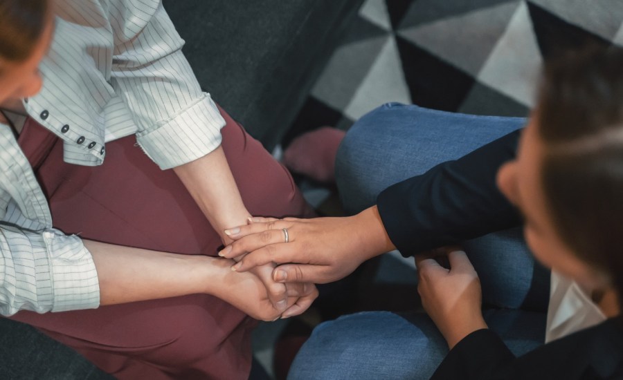 top down view of someone resting hands on another person's hands in support