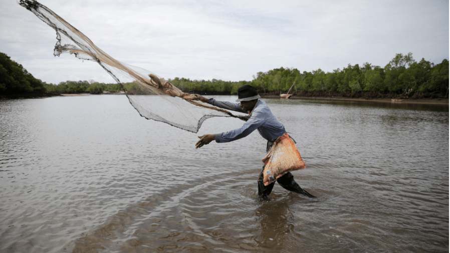 Fisherman Guni Mazeras, 62, casts a net backdropped by mangrove trees in Vanga, Kwale County, Kenya on Monday, June 13, 2022.