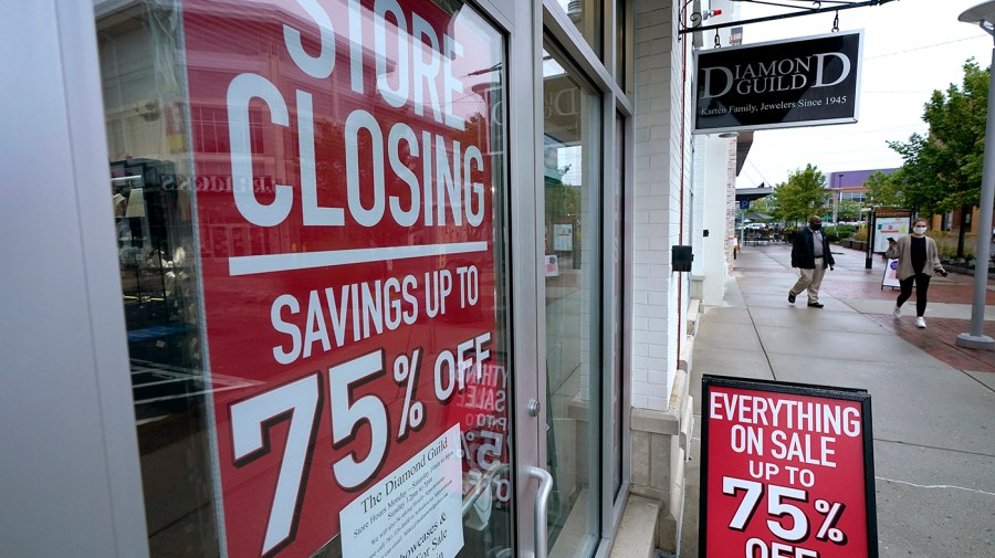 People pass a business with store closing signs