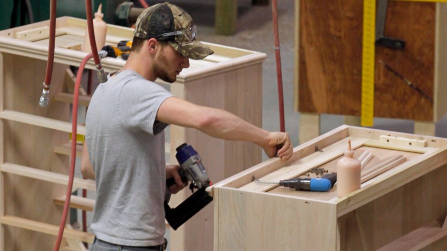 A worker attaches moulding to chests of drawers