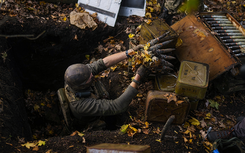 A Ukrainian territorial defense deminer takes Russian ammunition left behind