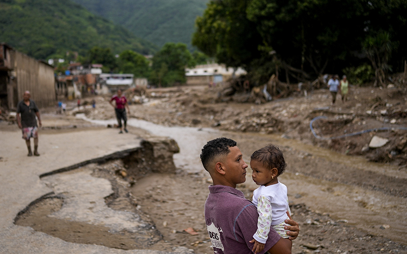 A man holds his daughter next to an overflow ravine