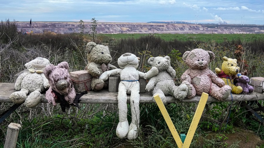 Worn teddy bears placed by climate activists sit on a wooden fence near the edge of the Garzweiler open-cast coal mine