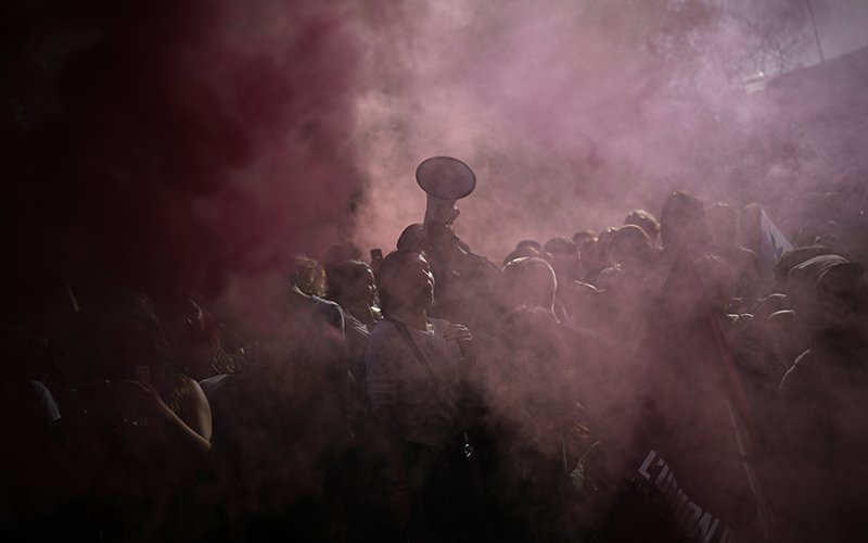 Protesters are obscured by the purple smoke of flares during a demonstration on Oct. 18 in Marseille, France