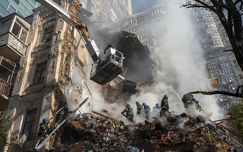 Firefighters work after a drone attack on buildings as smoke rises from the center in Kyiv, Ukraine