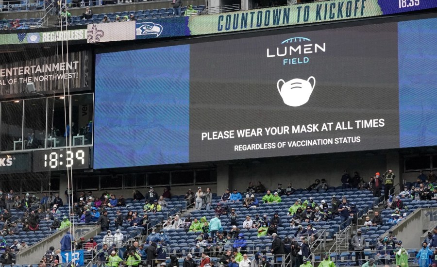 A sign reminds fans to wear masks during a football game.