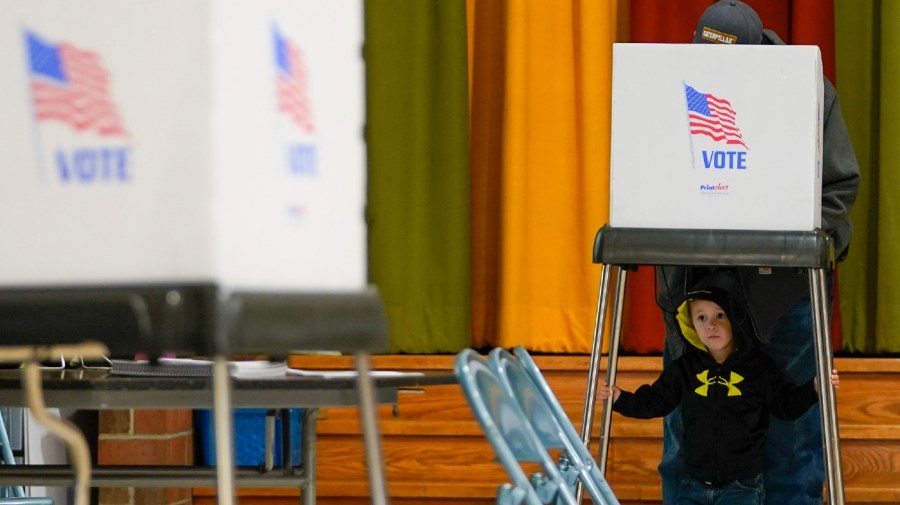 Jacob Lewis, 3, waits at a privacy booth as his grandfather, Robert Schroyer, fills out his ballot while voting at Sabillasville Elementary School, Tuesday, Nov. 8, 2022, in Sabillasville, Md.